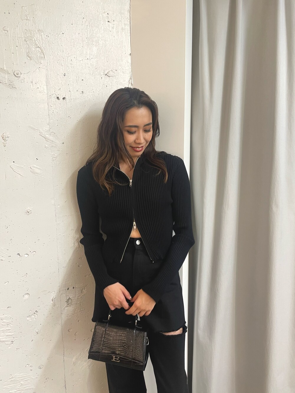 ブラック系のニット/セーター、ブラック系のショルダーバッグ、ホワイト系のブーツを着用したレディースの秋コーディネートの3枚目の写真