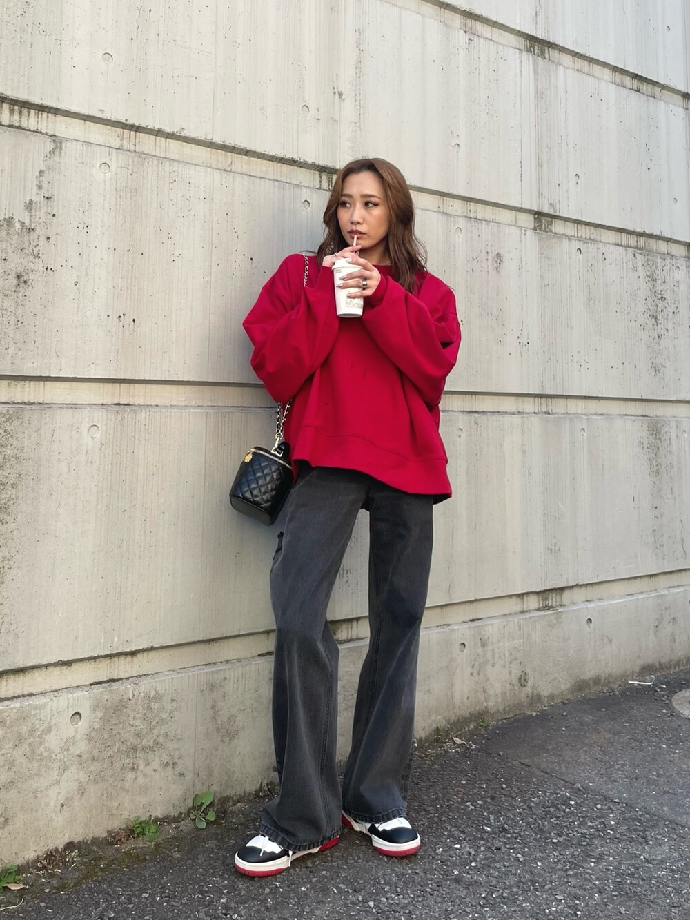 レッド系のスウェット、ブラック系のデニムパンツを着用したレディースの夏コーディネートの2枚目の写真