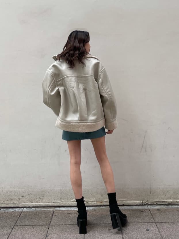 ホワイト系のブルゾン、ブルー系のスカート、ブラック系のTシャツ/カットソーを着用したレディースの冬コーディネートの2枚目の写真