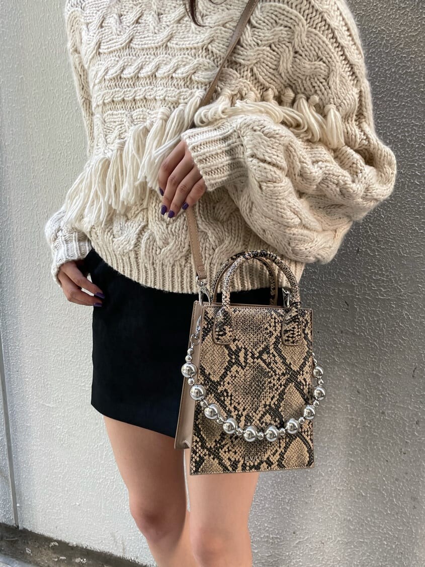 ベージュ系のブーツ、ホワイト系のニット/セーター、ブラック系のスカートを着用したレディースの秋コーディネートの4枚目の写真