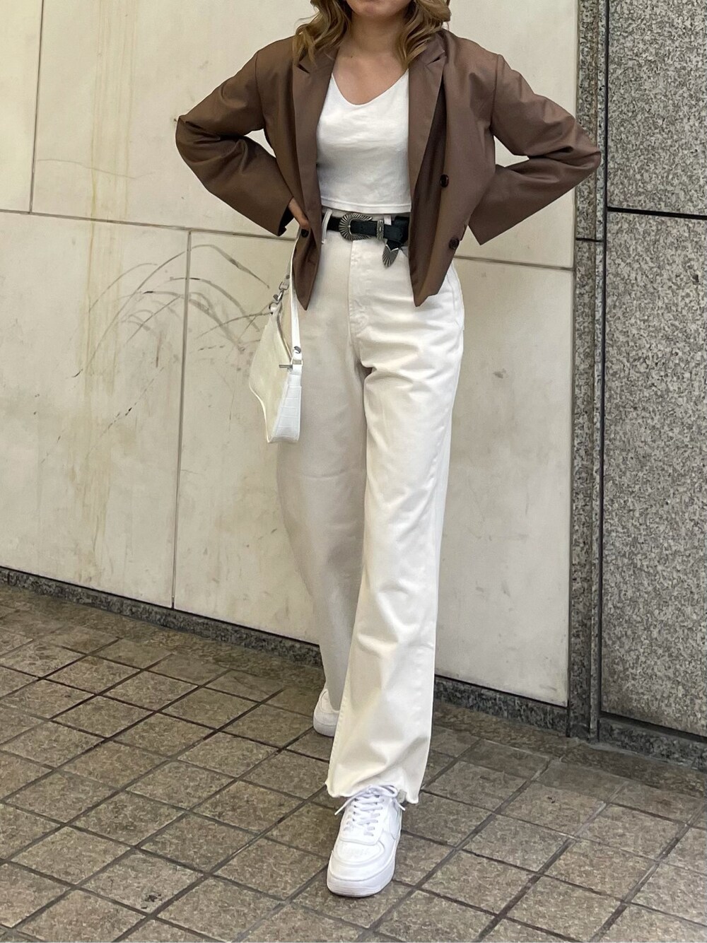 ホワイト系のデニムパンツ、ホワイト系のTシャツ/カットソー、ブラック系のベルトを着用したレディースの春コーディネートの2枚目の写真