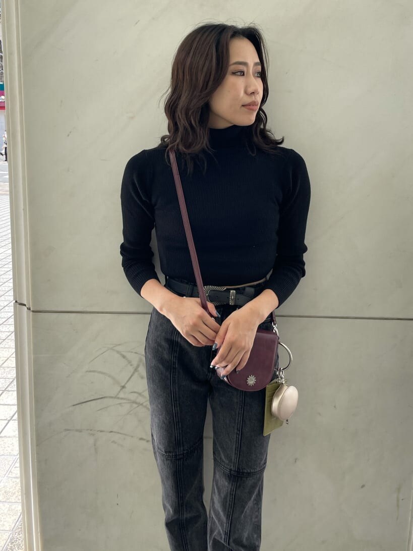 レッド系のショルダーバッグ、ブラック系のデニムパンツ、ブラック系のニット/セーターを着用したレディースの秋コーディネートの3枚目の写真