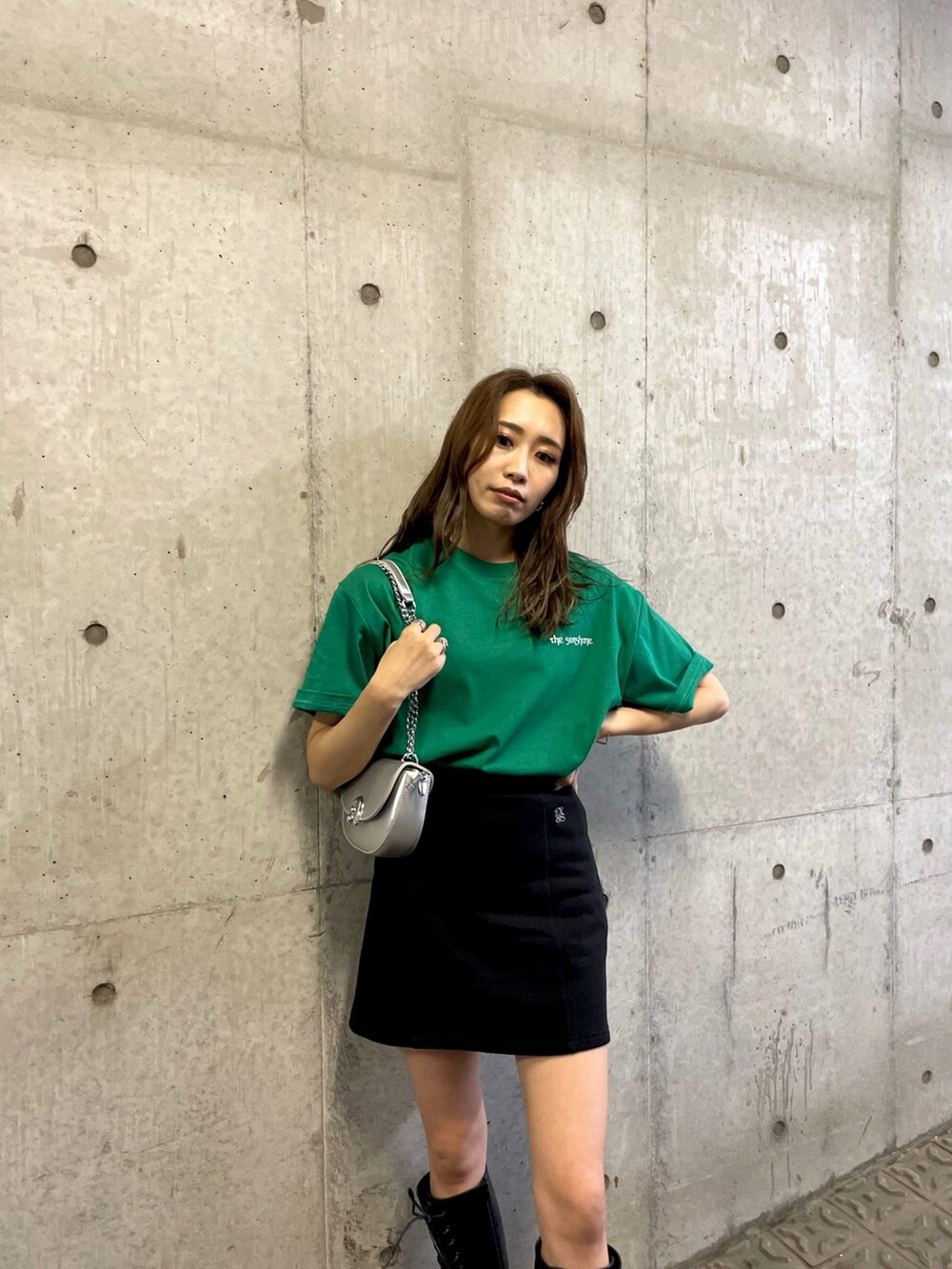 グリーン系のTシャツ/カットソー、ブラック系のスカート、ブラック系のブーツを着用したレディースの夏コーディネートの5枚目の写真