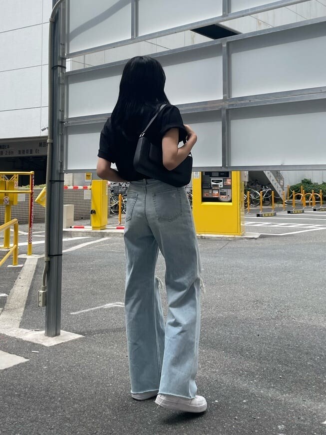 ブラック系のショルダーバッグ、ブルー系のデニムパンツ、ブラック系のTシャツ/カットソーを着用したレディースの夏コーディネートの2枚目の写真