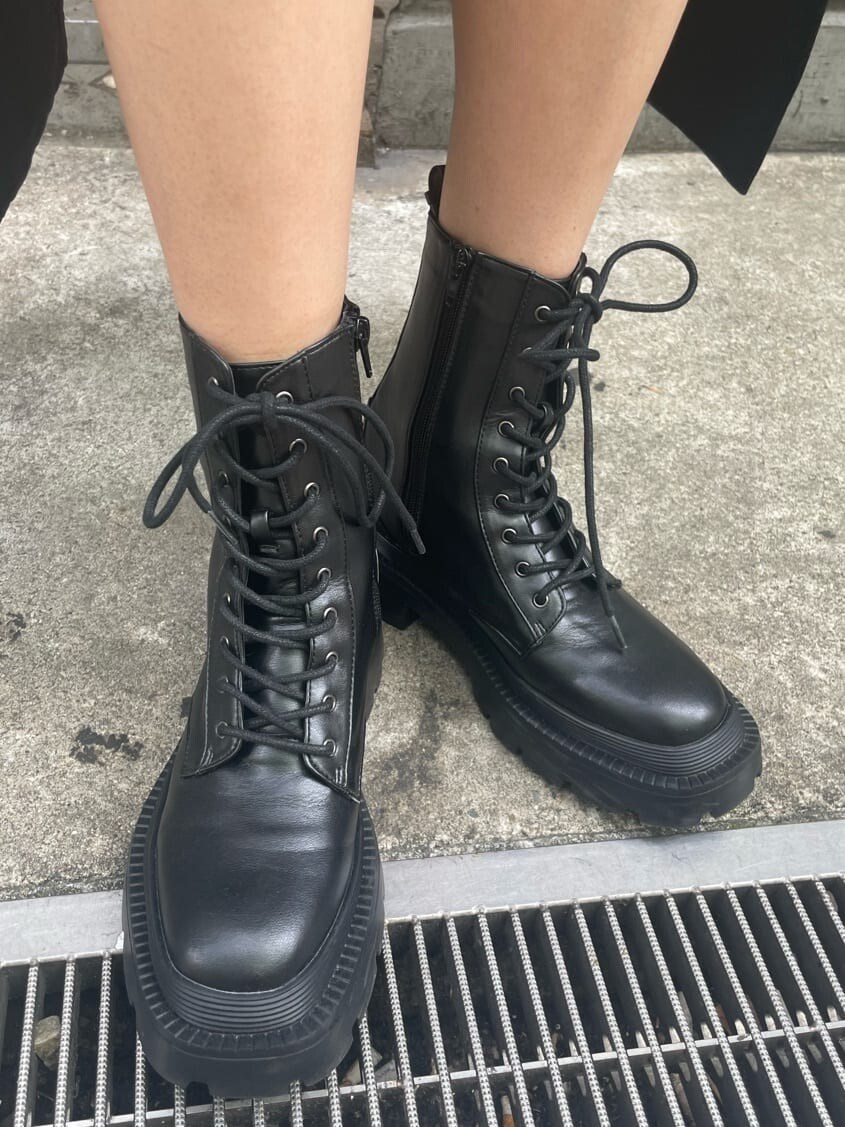 ブラック系のブーツ、ブラック系のトレンチコート、ブラック系のワンピースを着用したレディースの春コーディネートの10枚目の写真