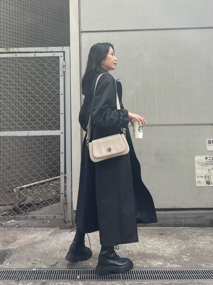 ブラック系のブーツ、ブラック系のトレンチコート、ブラック系のワンピースを着用したレディースの春コーディネートの7枚目の写真
