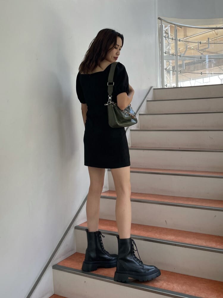 ブラック系のワンピース、ブラック系のブーツ、ベージュ系のショルダーバッグを着用したレディースの秋コーディネートの3枚目の写真