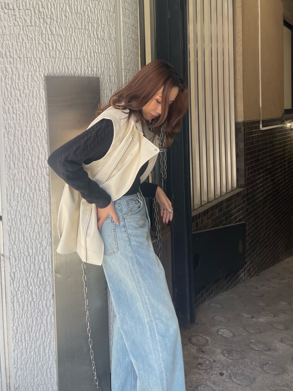 ブルー系のデニムパンツ、ブラック系のニット/セーター、ホワイト系のライダースジャケットを着用したレディースの冬コーディネートの5枚目の写真