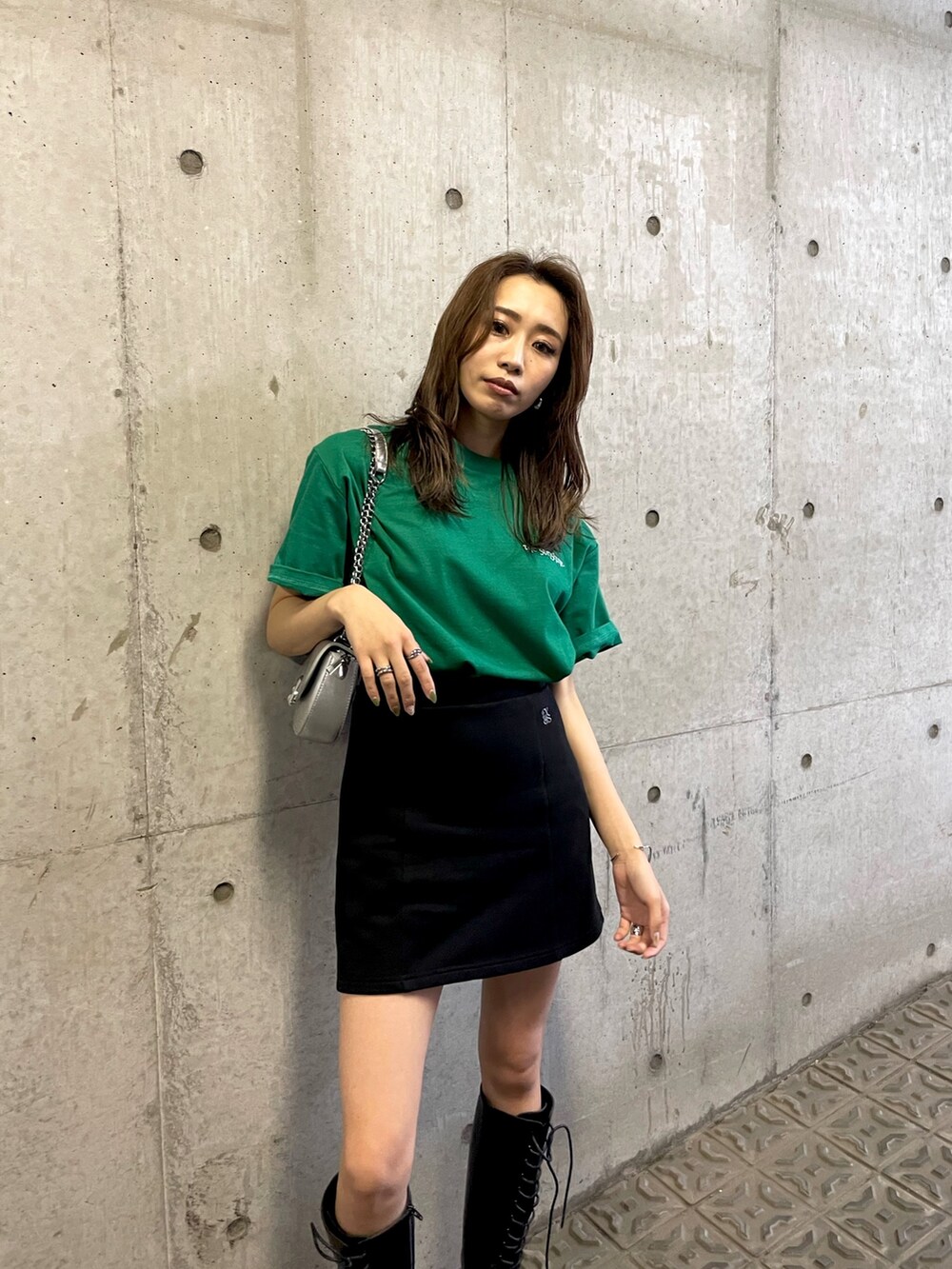 グリーン系のTシャツ/カットソー、ブラック系のスカート、ブラック系のブーツを着用したレディースの夏コーディネートの4枚目の写真