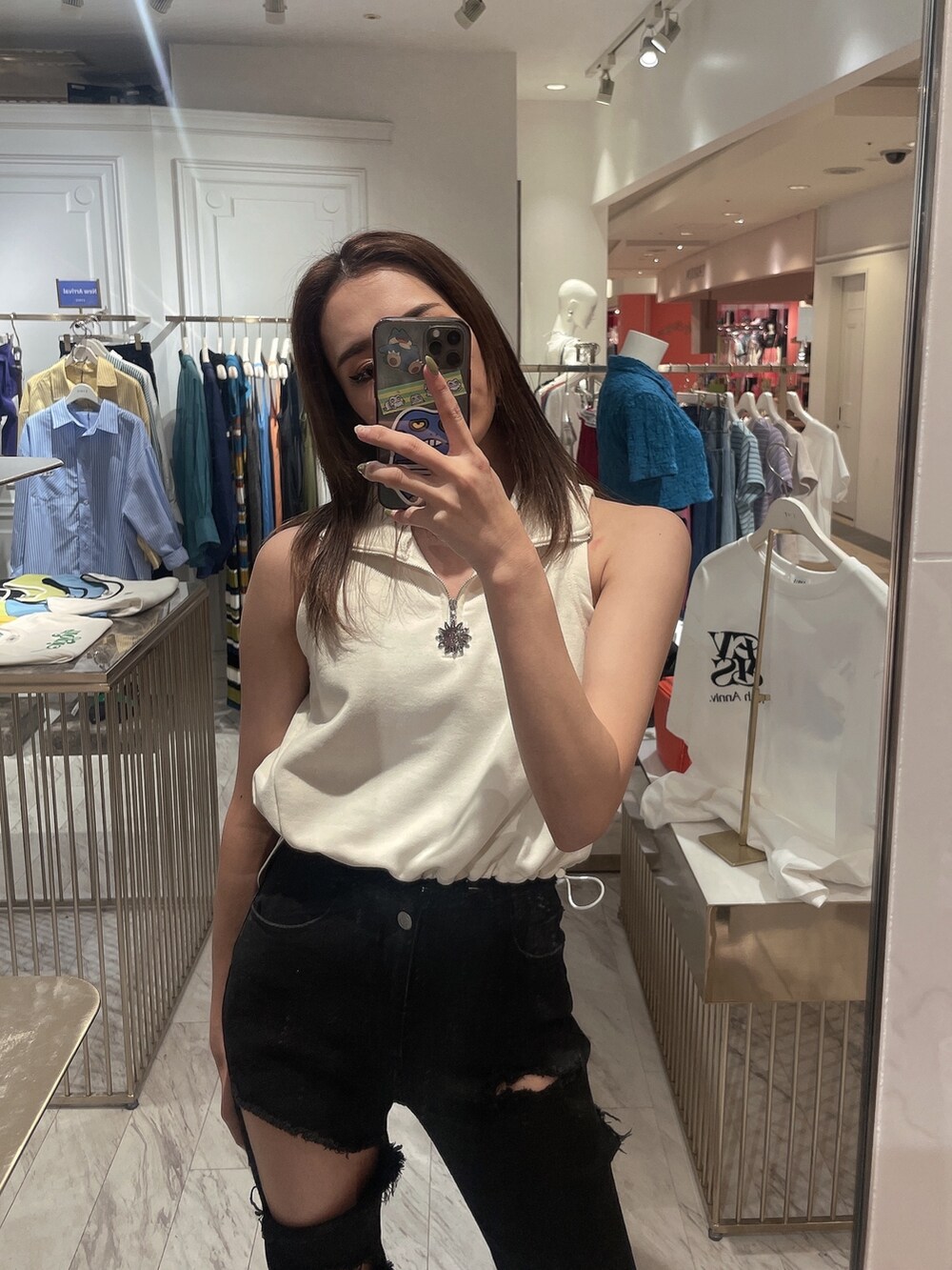 ブラック系のデニムパンツ、ブラック系のサンダル、ホワイト系のタンクトップを着用したレディースの春コーディネートの2枚目の写真