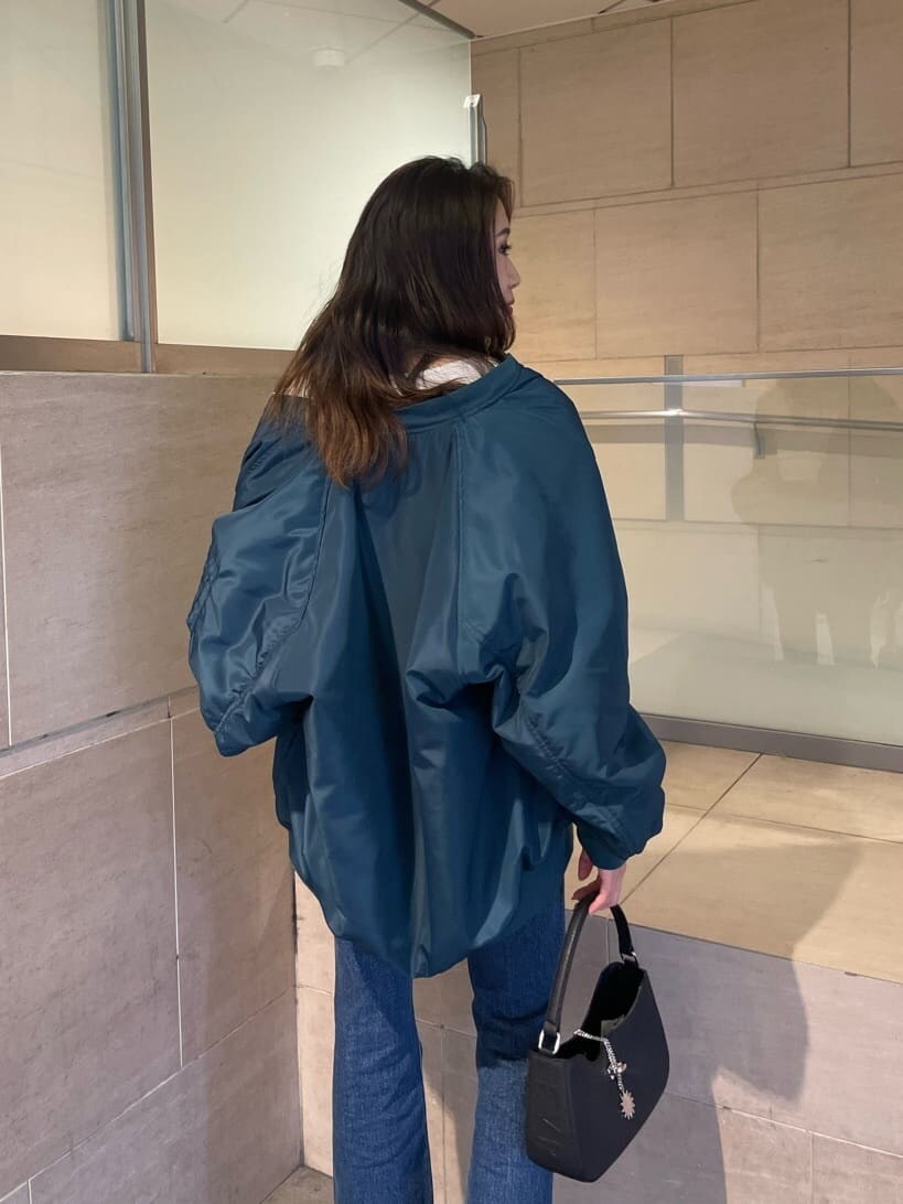 ブルー系のMA-1、ブラック系のブーツ、ブルー系のデニムパンツを着用したレディースの秋コーディネートの4枚目の写真