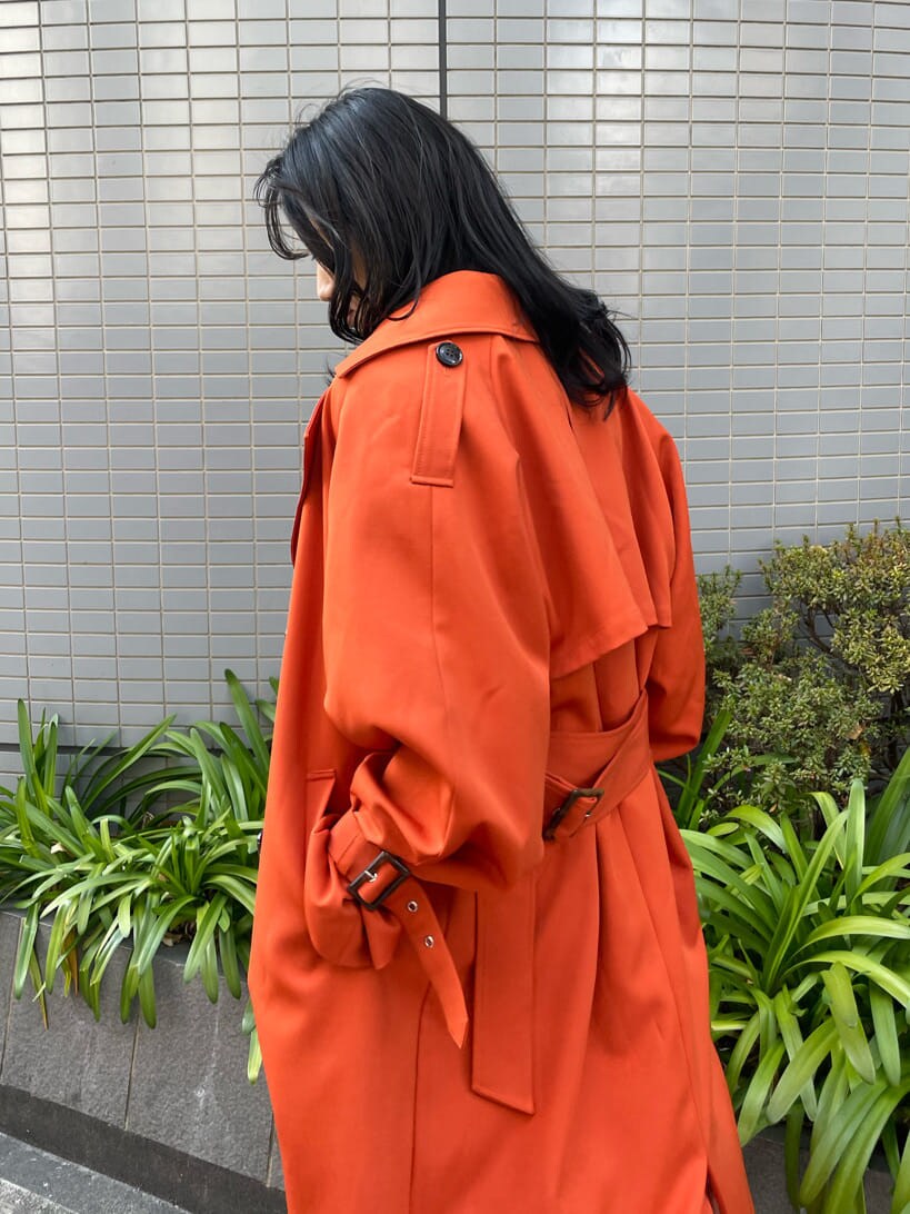 ブラック系のブーツ、オレンジ系のトレンチコート、ブルー系のデニムパンツを着用したレディースの春コーディネートの3枚目の写真