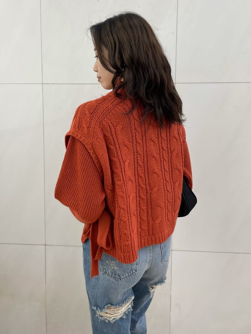 ブルー系のデニムパンツ、ブラック系のショルダーバッグ、オレンジ系のニット/セーターを着用したレディースの秋コーディネートの4枚目の写真