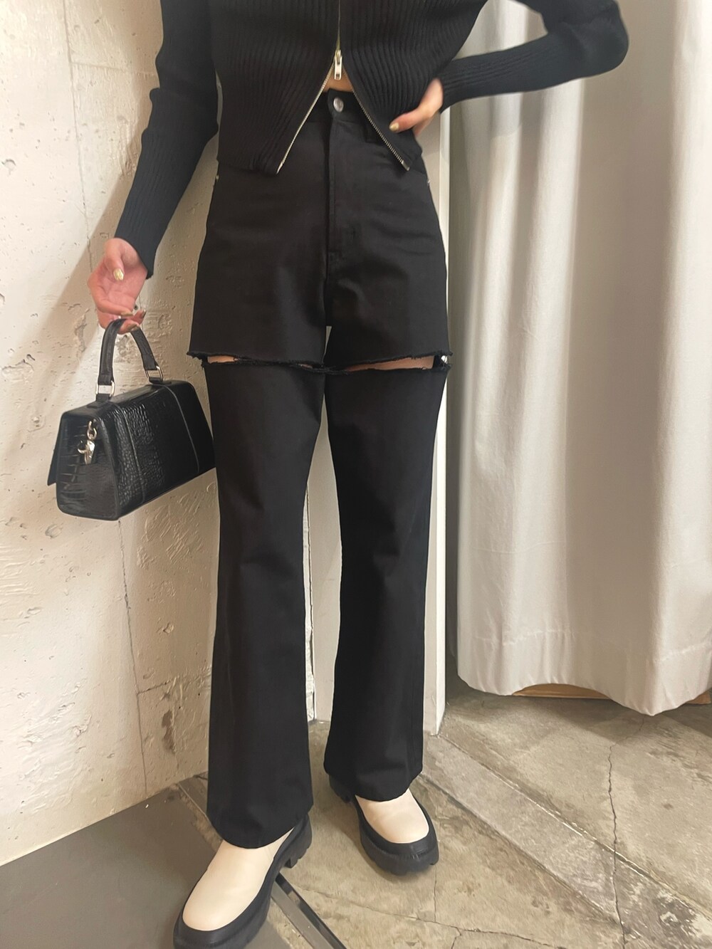 ブラック系のニット/セーター、ブラック系のショルダーバッグ、ホワイト系のブーツを着用したレディースの秋コーディネートの7枚目の写真