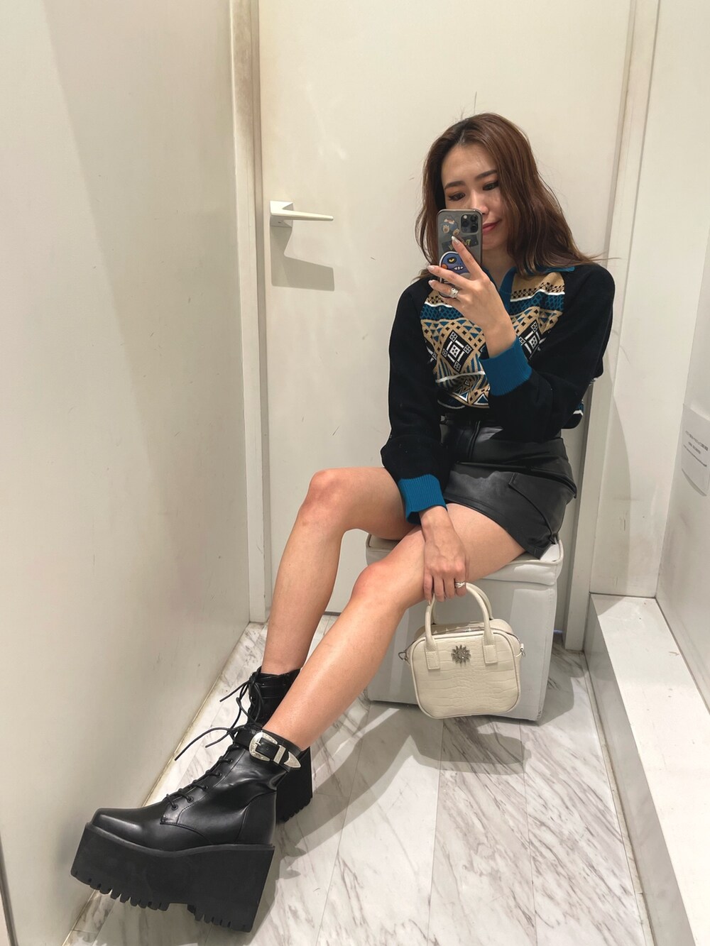 ブルー系のニット/セーター、ブラック系のスカート、ホワイト系のショルダーバッグを着用したレディースの冬コーディネートの2枚目の写真