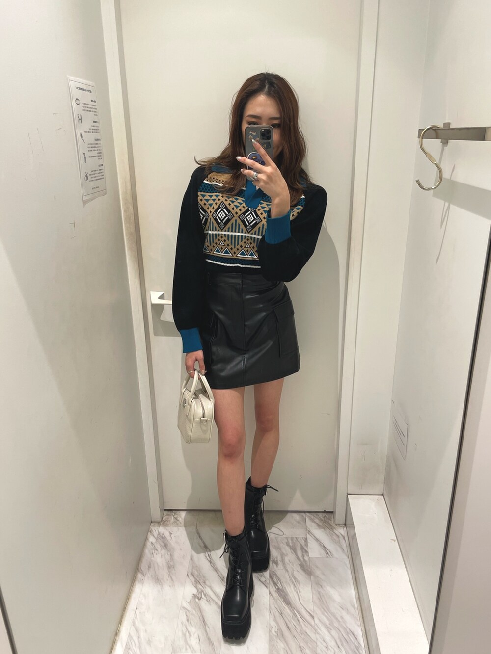 ブルー系のニット/セーター、ブラック系のスカート、ホワイト系のショルダーバッグを着用したレディースの冬コーディネートの3枚目の写真