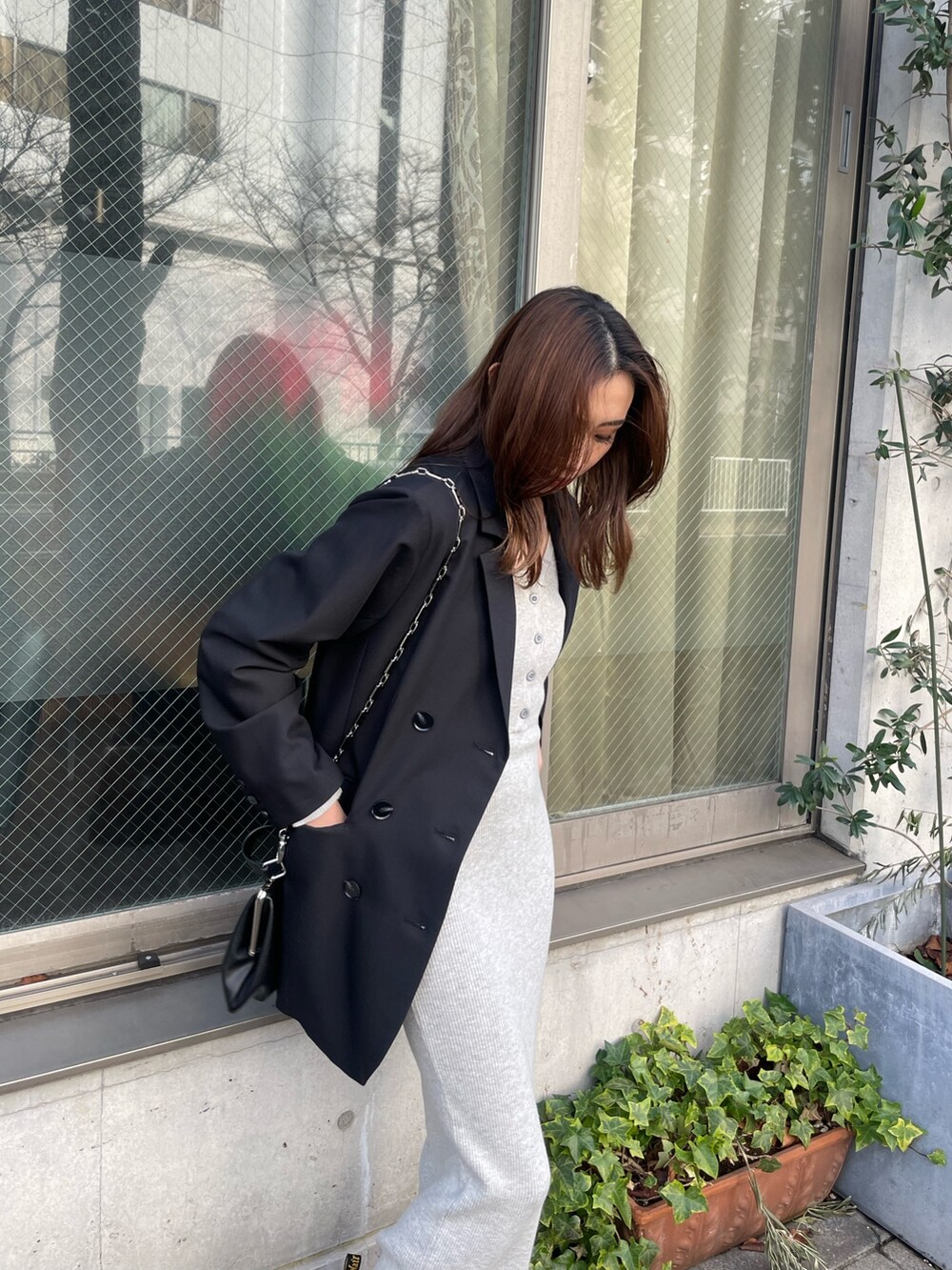 ブラック系のテーラードジャケット、グレー系のワンピース、ブラック系のショルダーバッグを着用したレディースの冬コーディネートの4枚目の写真