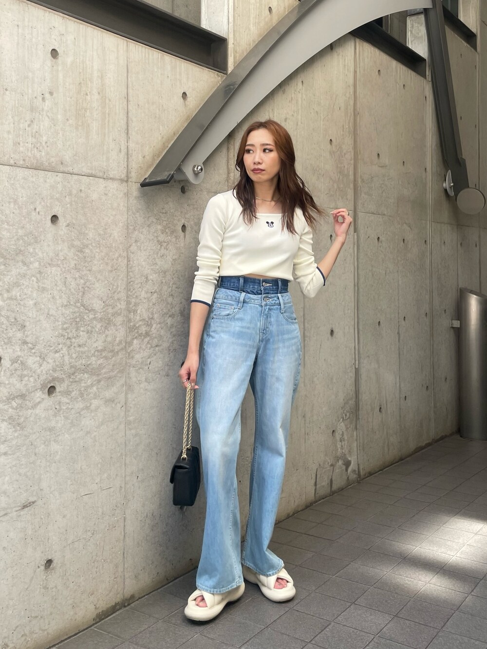 ホワイト系のニット/セーター、ブルー系のデニムパンツ、ブラック系のショルダーバッグを着用したレディースの夏コーディネートの4枚目の写真