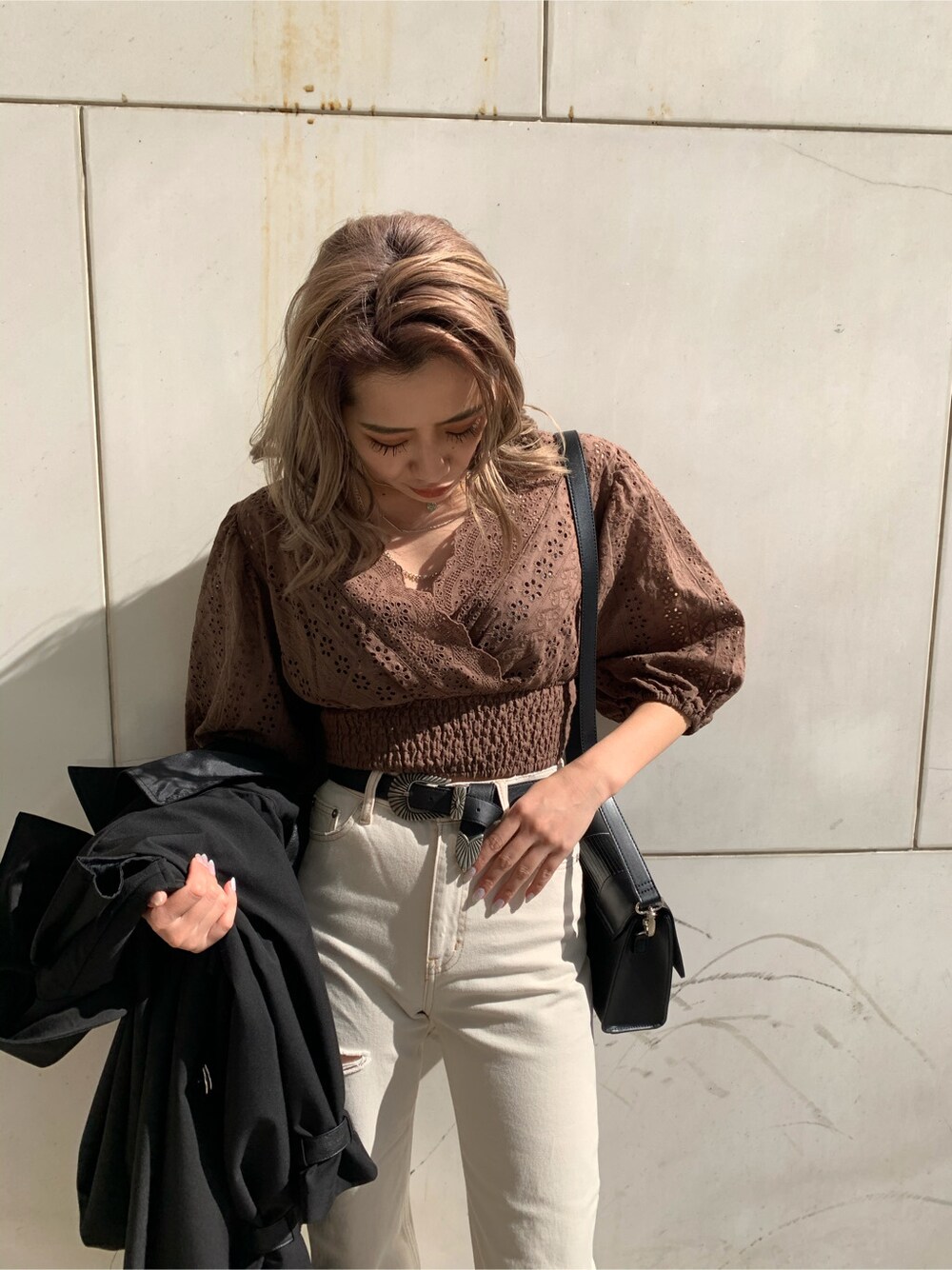 ブラック系のショルダーバッグ、ブラック系のトレンチコート、ホワイト系のデニムパンツを着用したレディースの冬コーディネートの4枚目の写真