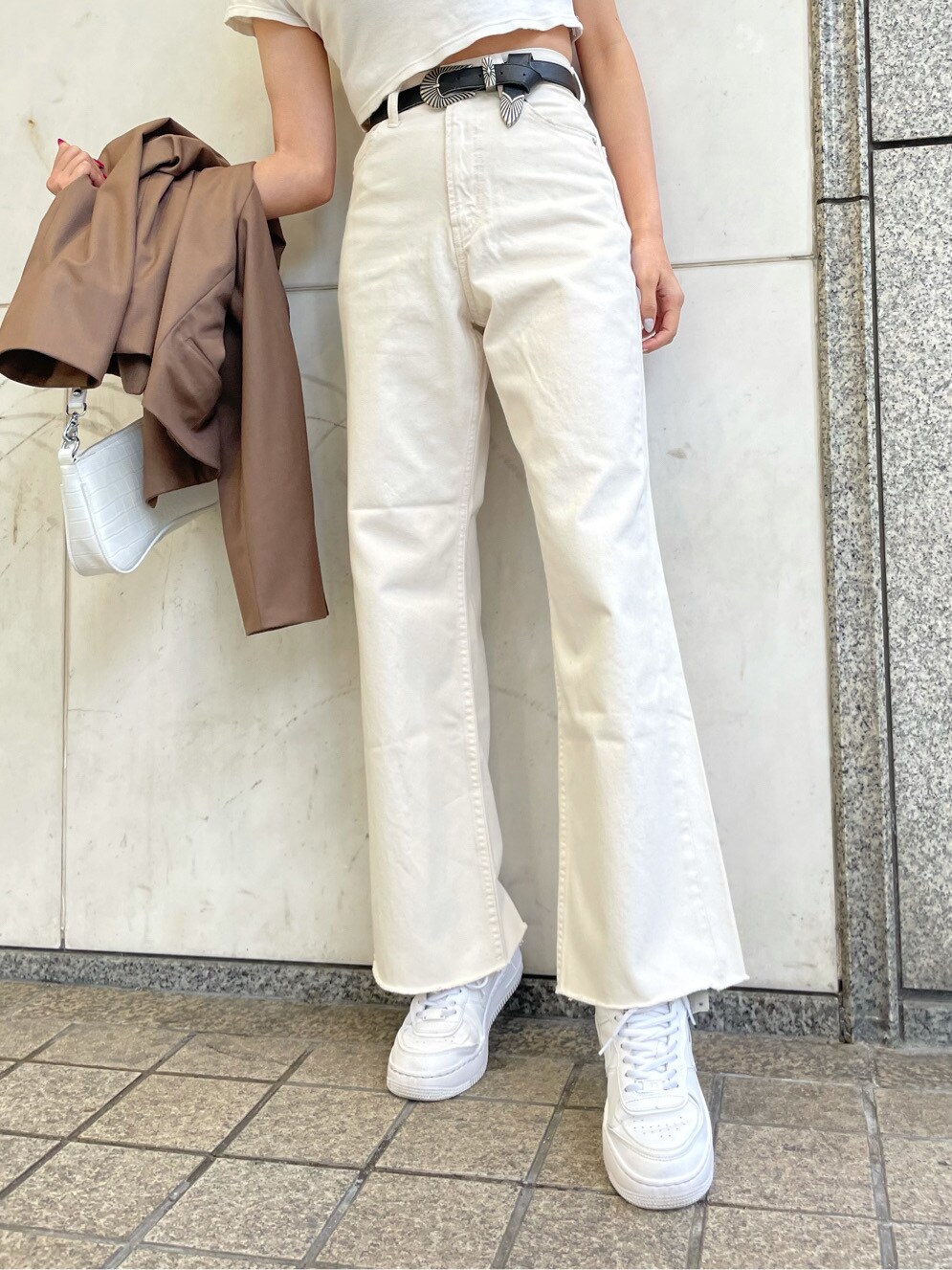 ホワイト系のデニムパンツ、ホワイト系のTシャツ/カットソー、ブラック系のベルトを着用したレディースの春コーディネートの4枚目の写真