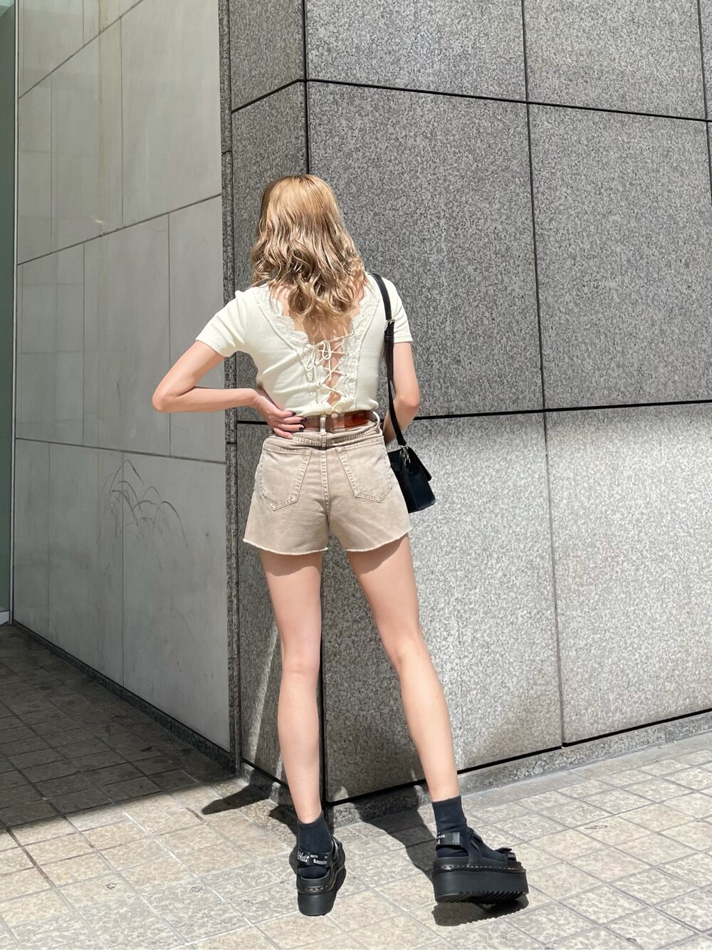 ブラック系のショルダーバッグ、ベージュ系のデニムパンツ、ホワイト系のTシャツ/カットソーを着用したレディースの春コーディネートの5枚目の写真