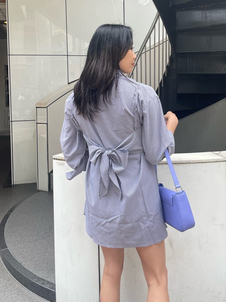 ブラック系のブーツ、ブラック系のワンピース、パープル系のショルダーバッグを着用したレディースの春コーディネートの3枚目の写真