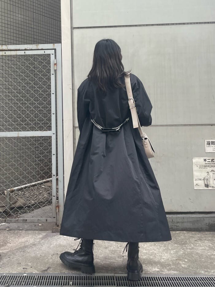 ブラック系のブーツ、ブラック系のトレンチコート、ブラック系のワンピースを着用したレディースの春コーディネートの4枚目の写真