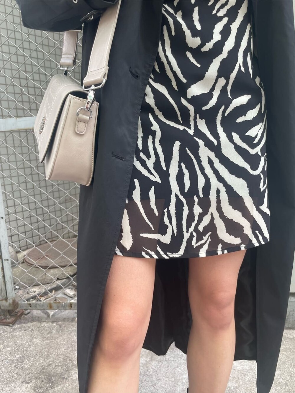 ブラック系のブーツ、ブラック系のトレンチコート、ブラック系のワンピースを着用したレディースの春コーディネートの8枚目の写真