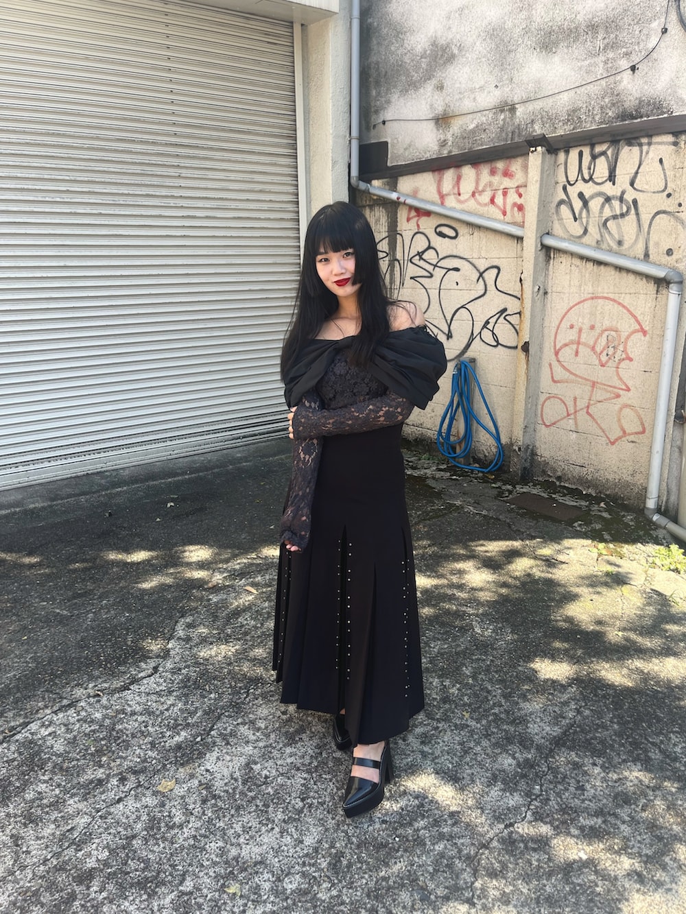 ブラック系のトップス、ブラック系のスカート、ブラック系のサンダルを着用したレディースの秋コーディネートの2枚目の写真