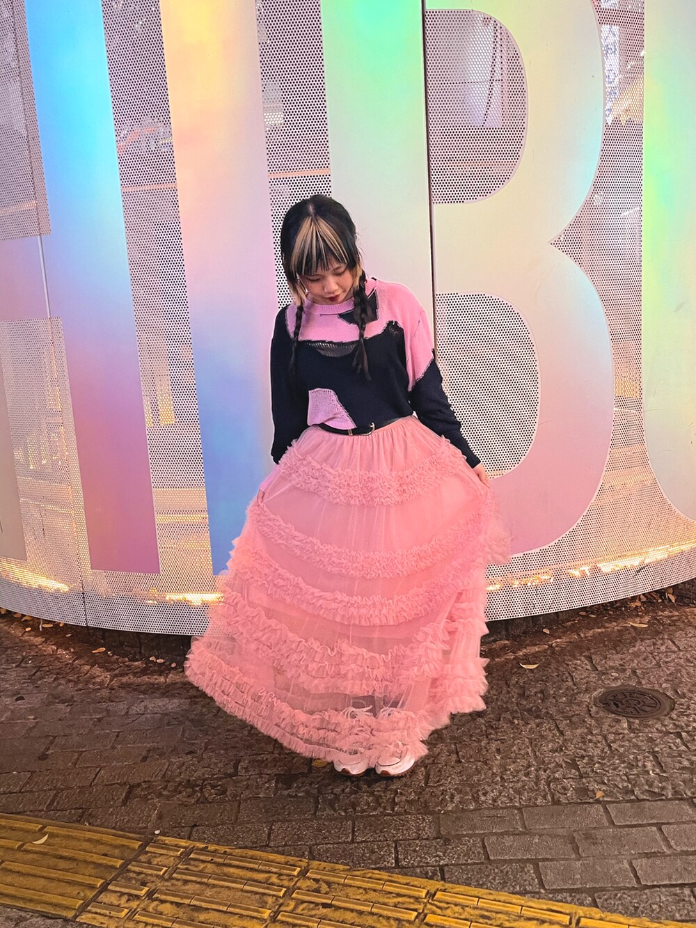 ブルー系のニット/セーター、ピンク系のスカート、ブラック系のスニーカーを着用したレディースの春コーディネートの2枚目の写真