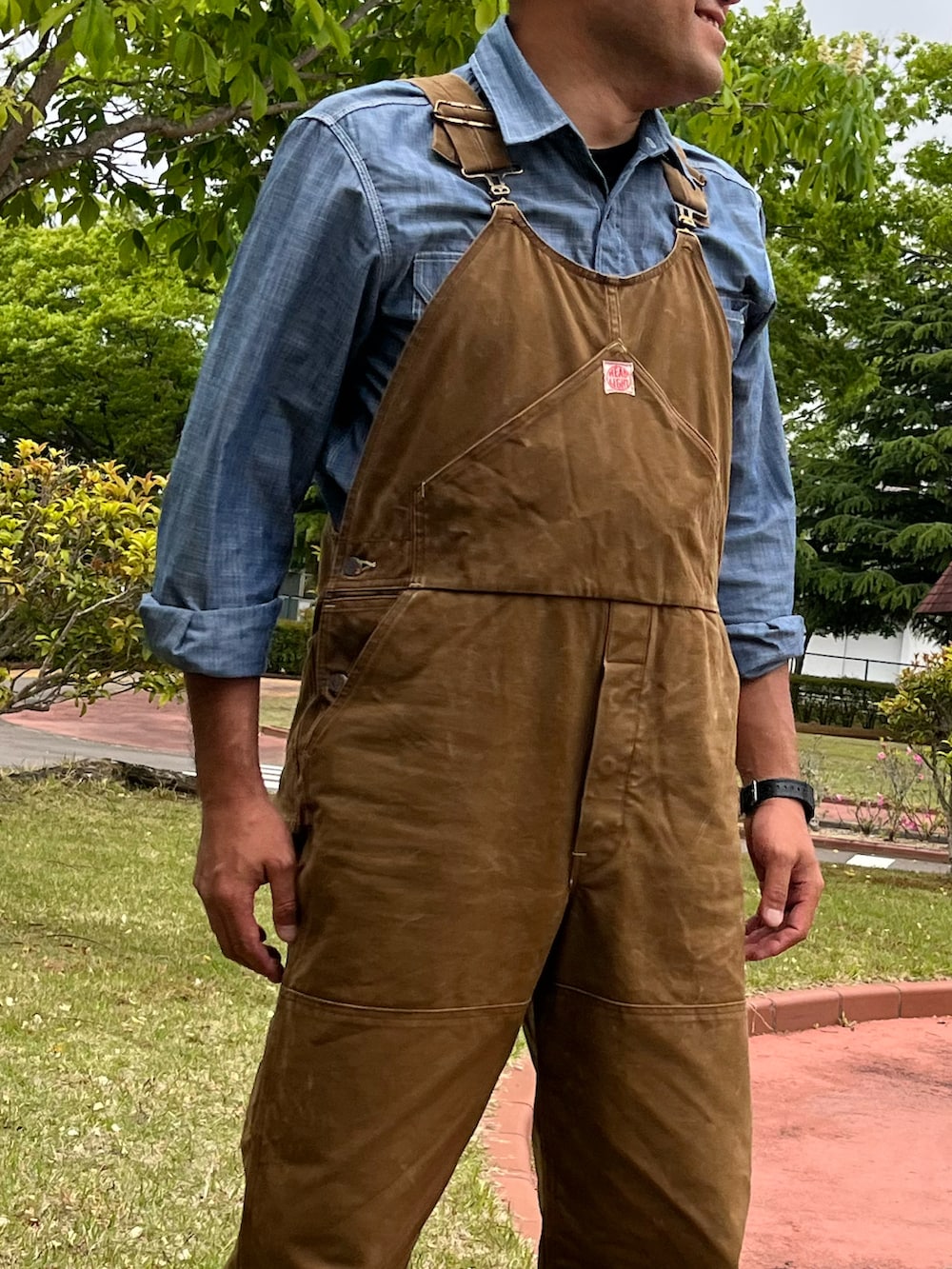 ブルー系のシャツ/ブラウス、ブラック系のブーツ、ブラウン系のサロペット/オーバーオールを着用したメンズの春コーディネートの2枚目の写真