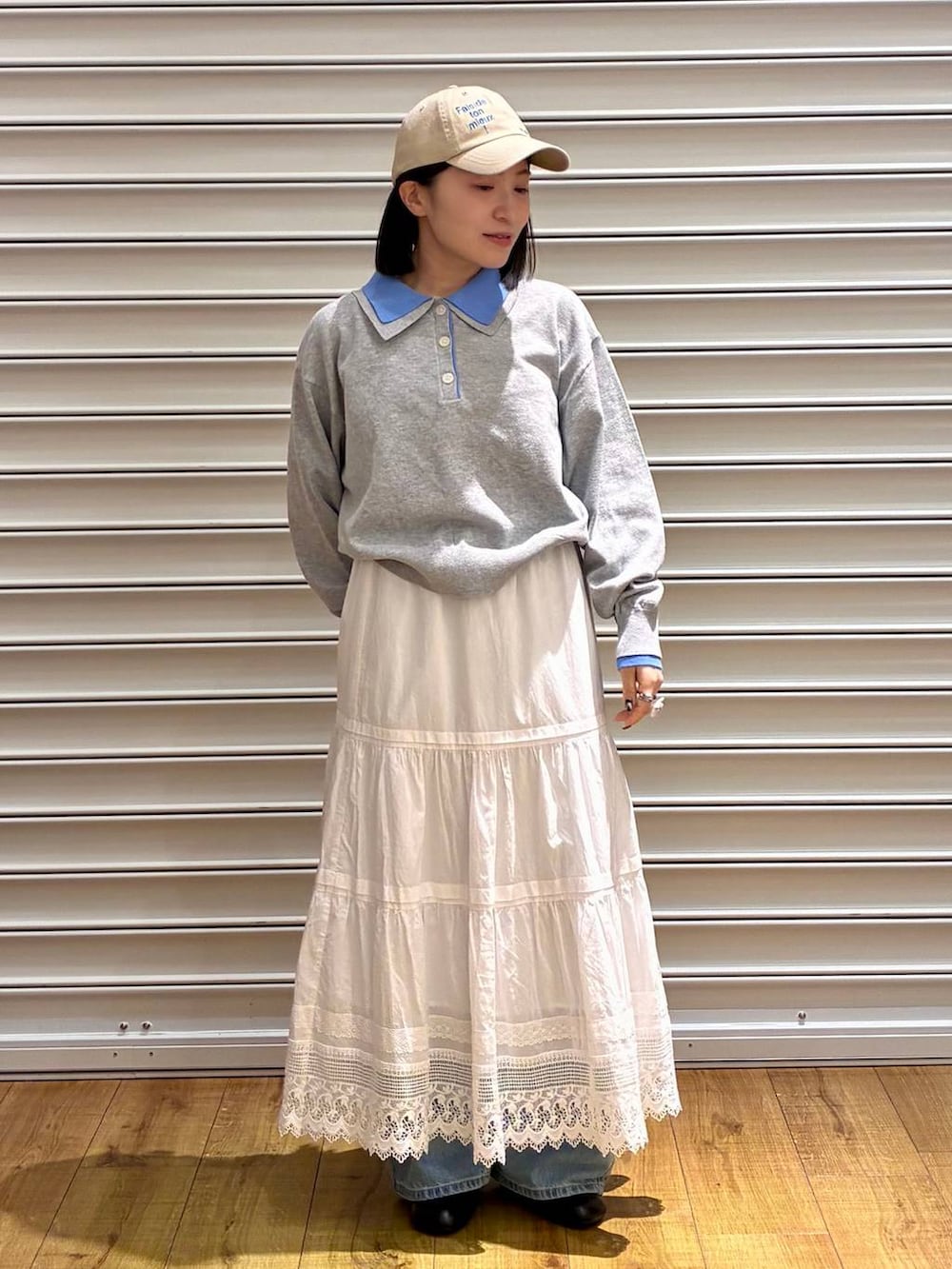 ブルー系のデニムパンツ、ブラック系のサンダル、ホワイト系のスカートを着用したレディースの春コーディネートの3枚目の写真