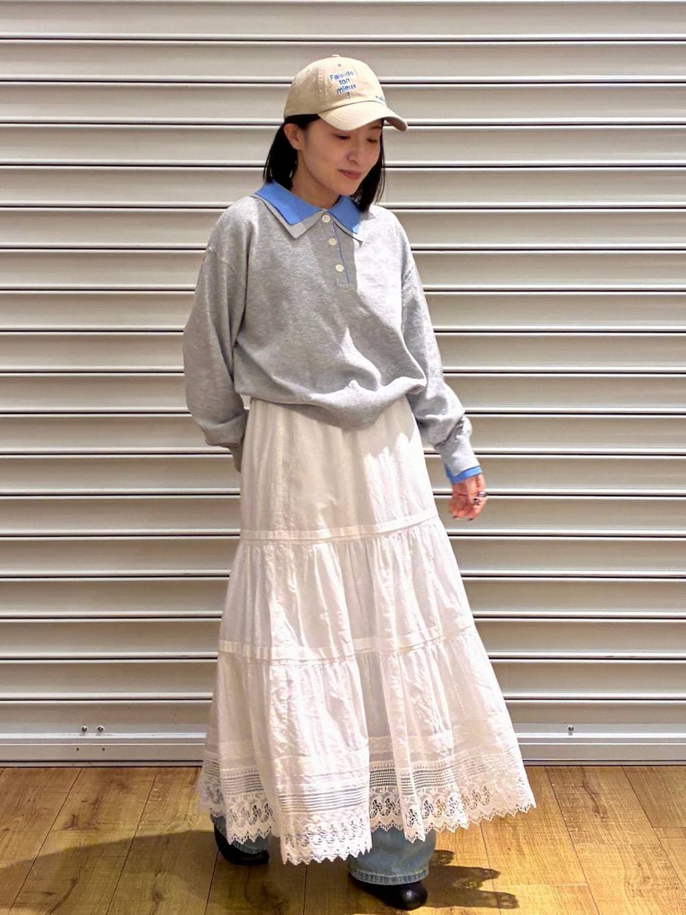 ブルー系のデニムパンツ、ブラック系のサンダル、ホワイト系のスカートを着用したレディースの春コーディネートの2枚目の写真