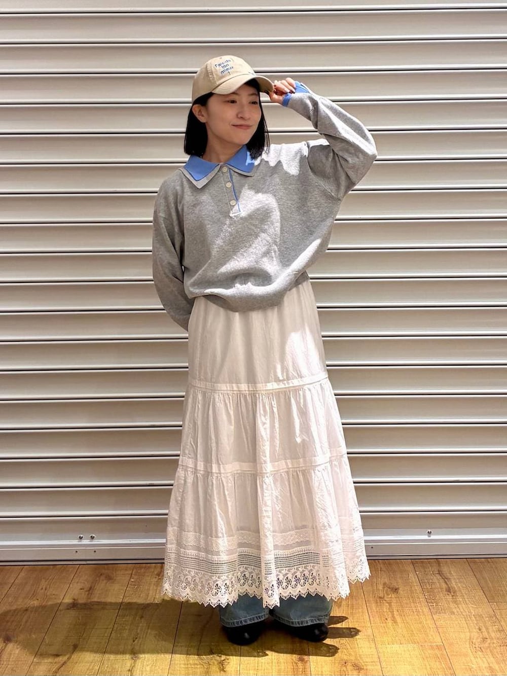 ブルー系のデニムパンツ、ブラック系のサンダル、ホワイト系のスカートを着用したレディースの春コーディネートの5枚目の写真