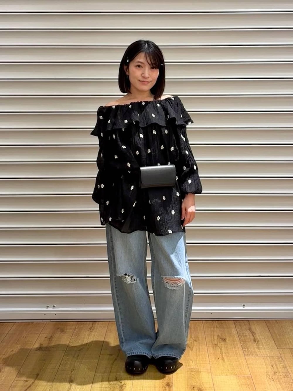 ブルー系のデニムパンツ、ブラック系のサンダル、ブラック系のボディバッグ/ウエストポーチを着用したレディースの春コーディネートの6枚目の写真