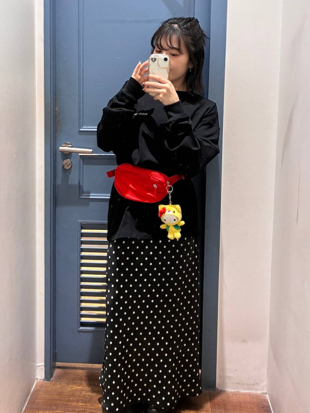 ブラック系のスカート、レッド系のボディバッグ/ウエストポーチ、ブラック系のTシャツ/カットソーを着用したレディースの春コーディネートの2枚目の写真