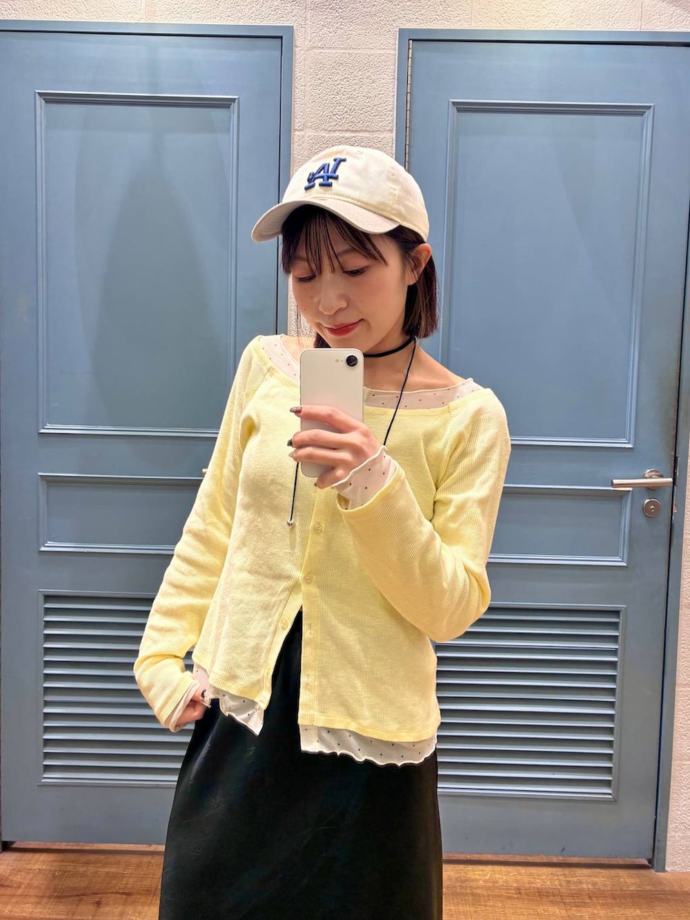 ブラック系のスカート、ブラウン系のサンダル、イエロー系のTシャツ/カットソーを着用したレディースの冬コーディネートの2枚目の写真