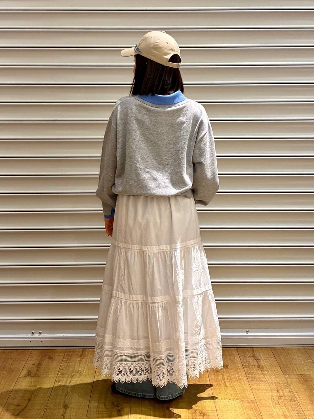 ブルー系のデニムパンツ、ブラック系のサンダル、ホワイト系のスカートを着用したレディースの春コーディネートの4枚目の写真