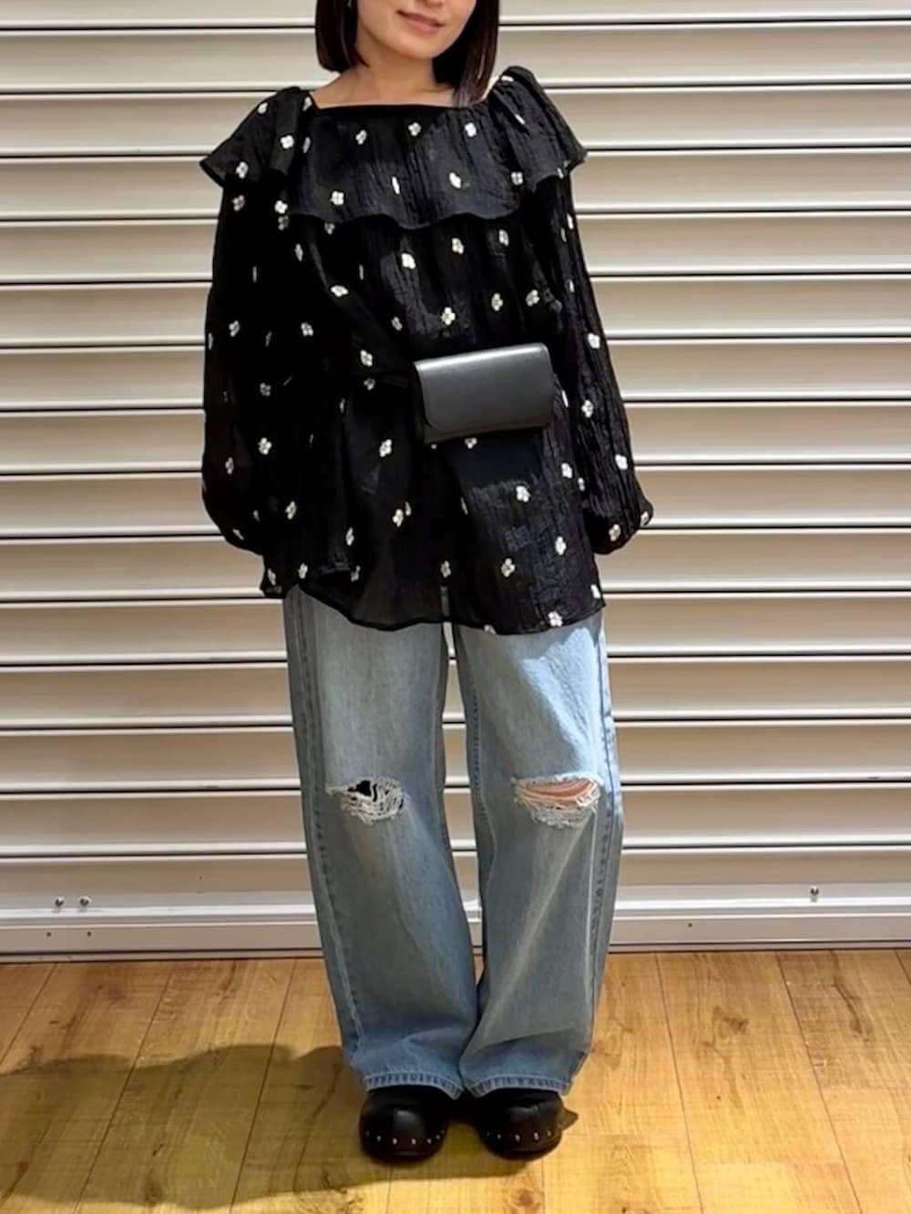 ブルー系のデニムパンツ、ブラック系のサンダル、ブラック系のボディバッグ/ウエストポーチを着用したレディースの春コーディネートの2枚目の写真