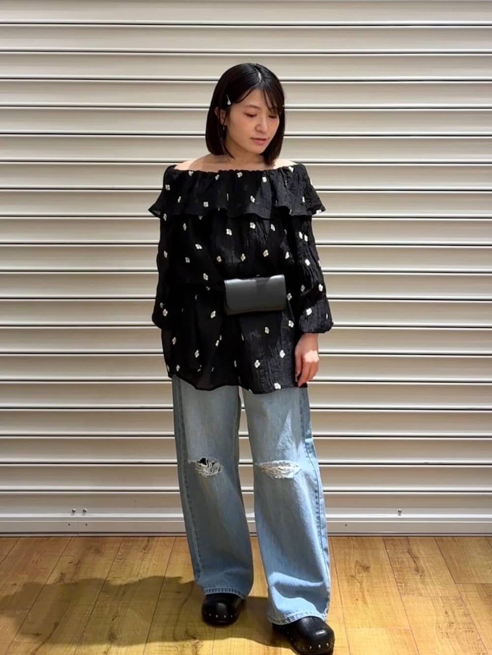 ブルー系のデニムパンツ、ブラック系のサンダル、ブラック系のボディバッグ/ウエストポーチを着用したレディースの春コーディネートの3枚目の写真