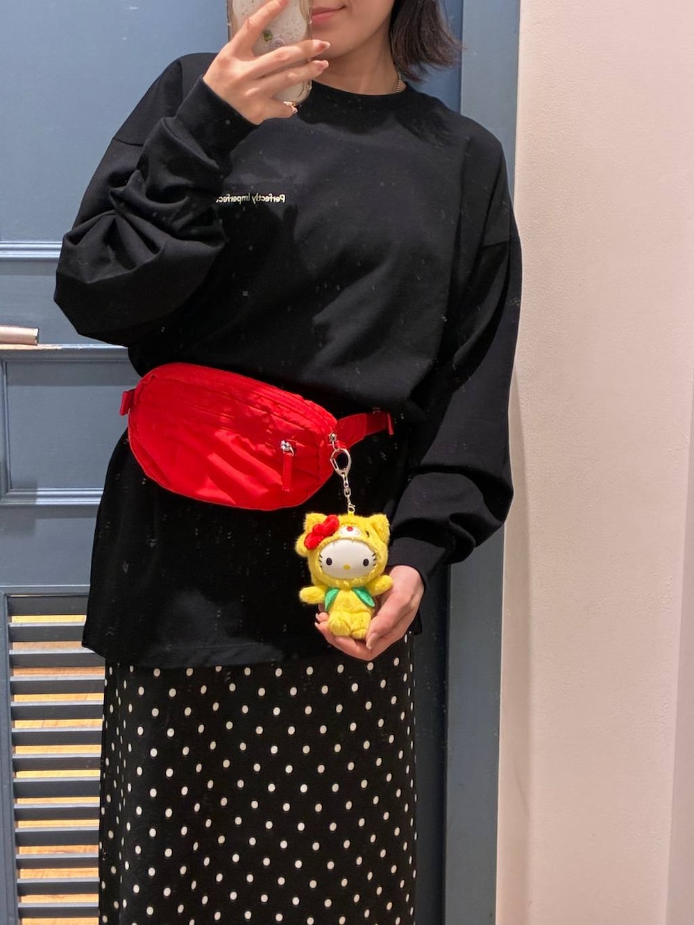 ブラック系のスカート、レッド系のボディバッグ/ウエストポーチ、ブラック系のTシャツ/カットソーを着用したレディースの春コーディネートの3枚目の写真