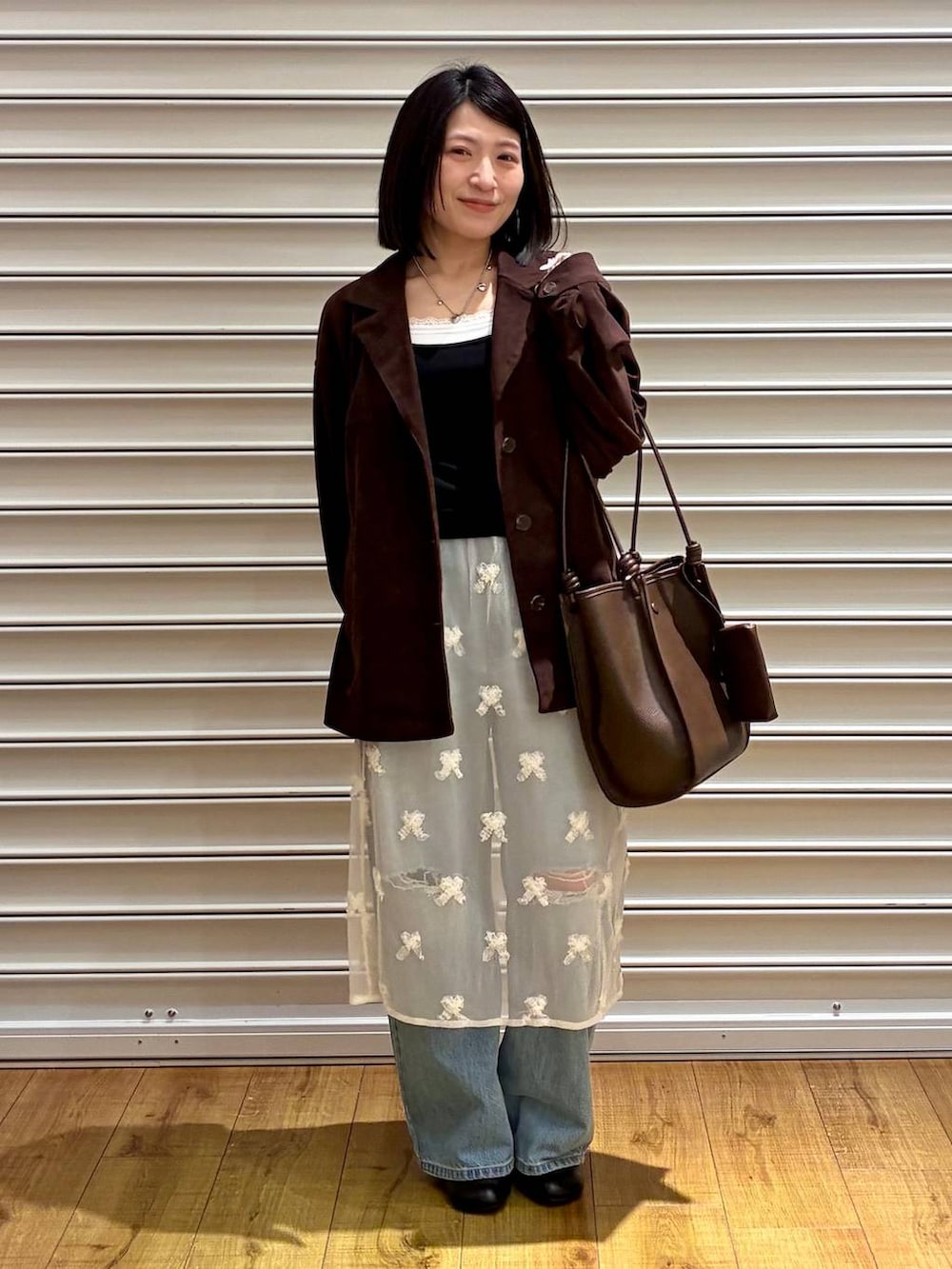 ブルー系のデニムパンツ、ブラウン系のテーラードジャケット、ブラック系のサンダルを着用したレディースの春コーディネートの5枚目の写真