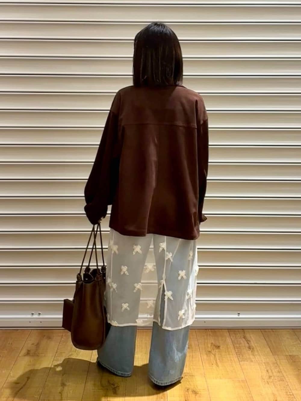 ブルー系のデニムパンツ、ブラウン系のテーラードジャケット、ブラック系のサンダルを着用したレディースの春コーディネートの4枚目の写真