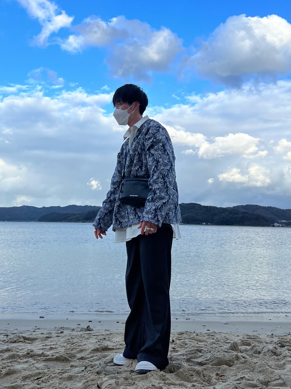 ブルー系のダウンベスト、ブラック系のスラックス、グレー系のスニーカーを着用したメンズの春コーディネートの2枚目の写真