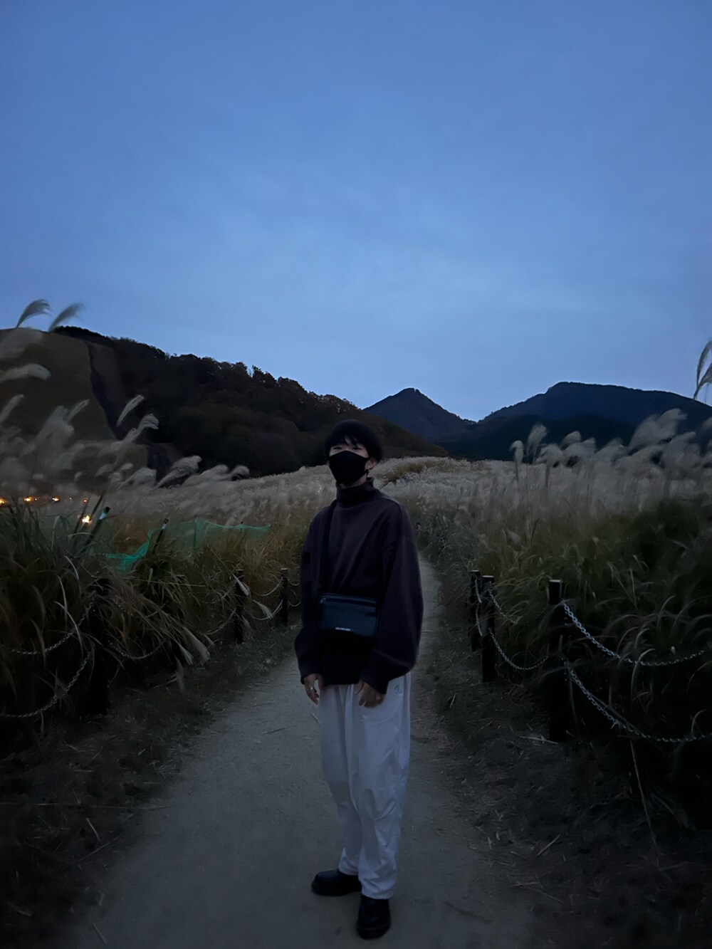 ブラウン系のニット/セーター、ブラック系のショルダーバッグ、ホワイト系のチノパンツを着用したメンズの春コーディネートの3枚目の写真