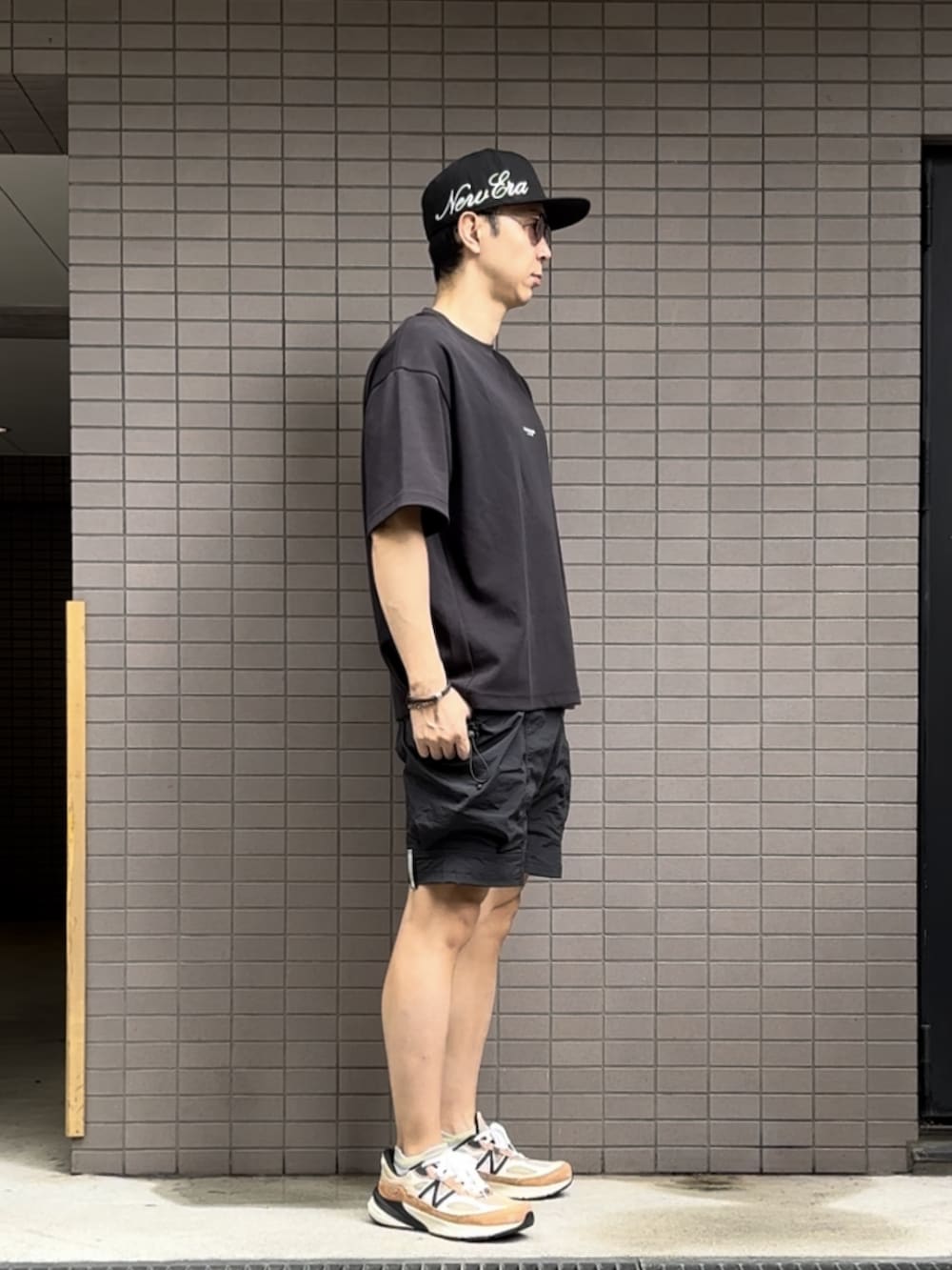 ブラック系のTシャツ/カットソー、ブラック系のその他パンツ、オレンジ系のスニーカーを着用したメンズの夏コーディネートの2枚目の写真