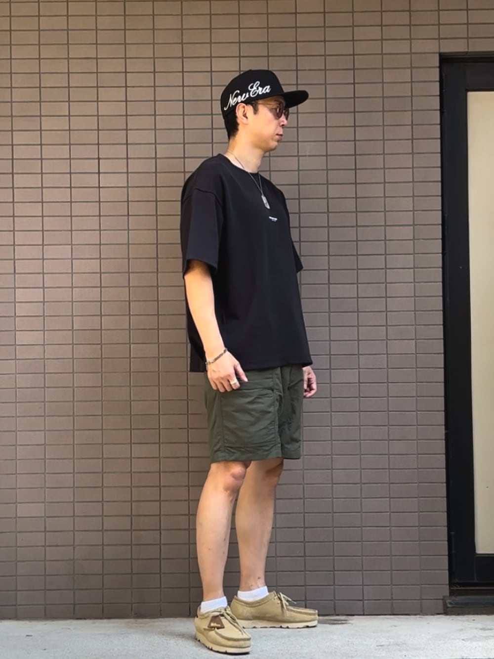 ブラック系のTシャツ/カットソー、ベージュ系のスニーカー、グリーン系のパンツを着用したメンズの夏コーディネートの2枚目の写真