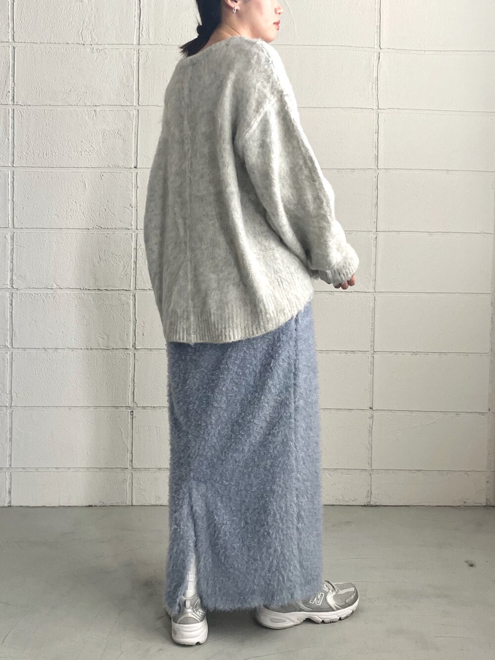 シルバー系のスニーカー、ブルー系のスカート、グレー系のニット/セーターを着用したレディースの秋コーディネートの2枚目の写真