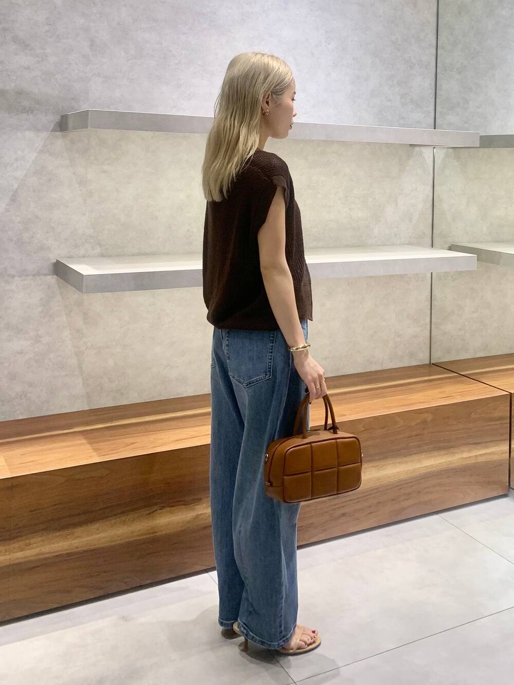 ベージュ系のスリッポン、ブラウン系のハンドバッグ、ブルー系のデニムパンツを着用したレディースの夏コーディネートの4枚目の写真