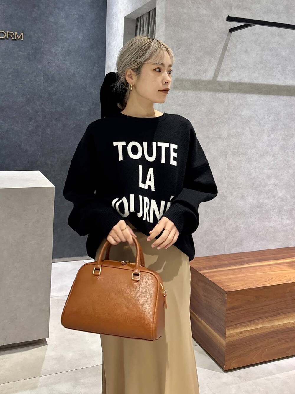 イエロー系のボストンバッグ、ブラック系のローファー、ブラック系のニット/セーターを着用したレディースの冬コーディネートの2枚目の写真